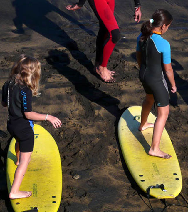 Niños aprendiendo a practicar surf en sus tablas sobre la arena