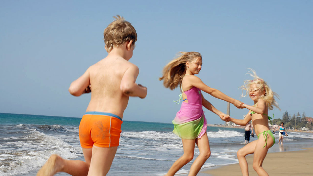 Tres niños juegan en la playa de Maspalomas