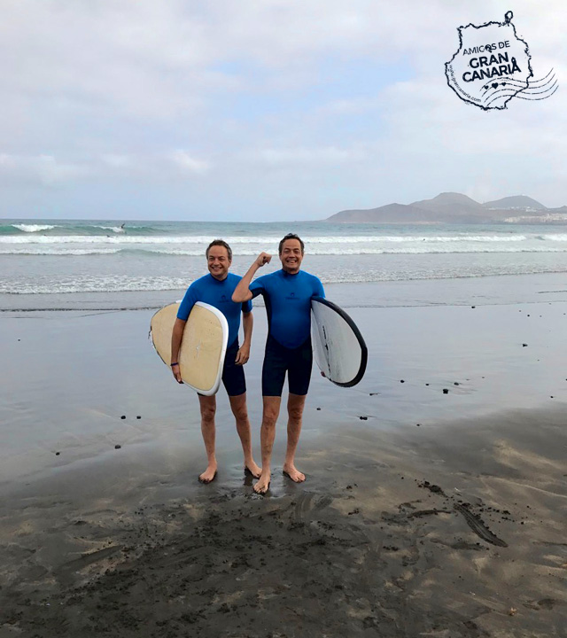 Los cocineros y Hermanos Torres salen del agua con las tablas de surf bajo el brazo en La Cícer en la Playa de Las Canteras