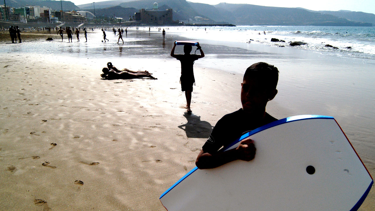 Niño en la playa con su tabla de bodyboard